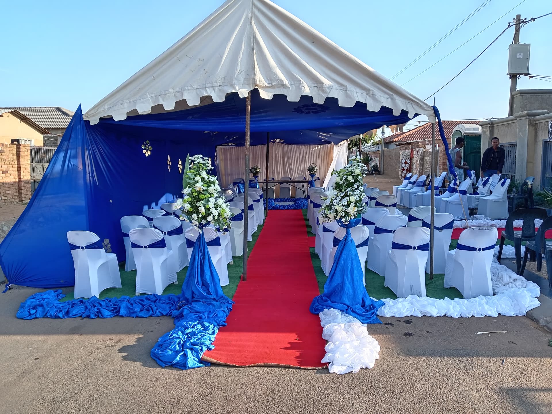 White tent with blue draping and red-carpet aisle