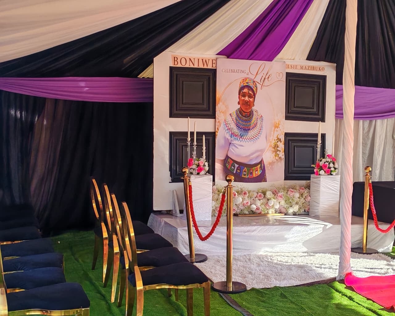 Memorial stage with backdrop, candles and floral arrangements
